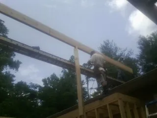 Carpenter setting a ridge beam over a new addition frame — Ice Dam Removal by Roofing Brothers in Clyo