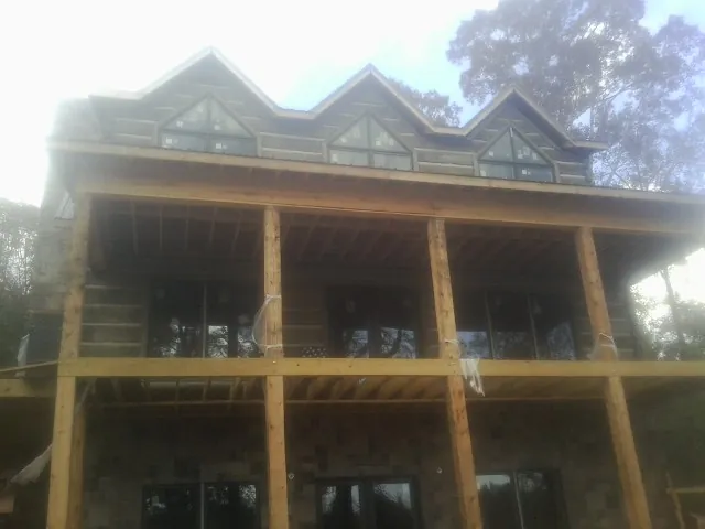 Dormers and porch framing on a large log home under construction — Roof Coating work by our crew in Clyo