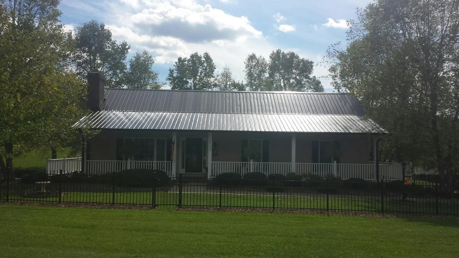 Gray metal roof on a brick ranch with a full width front porch — Gutter Guard Installation work by our crew in Clyo
