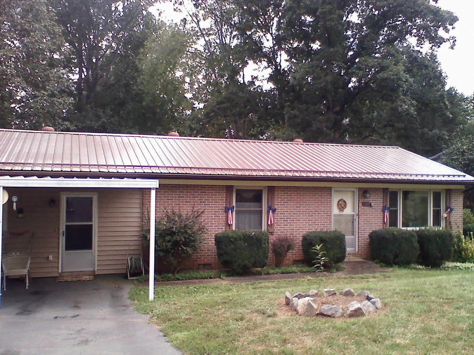 Bronze metal roof and carport on a brick ranch home — Roof Repair work by our crew in Clyo