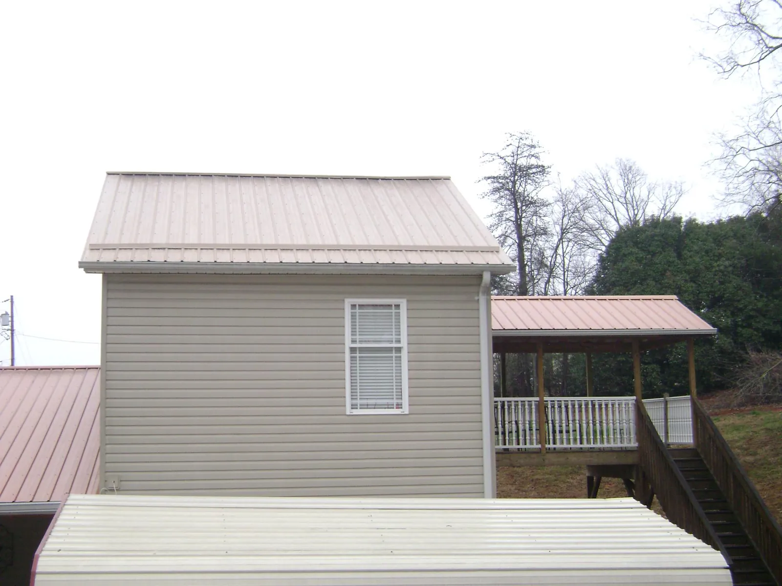 Tan metal roofs on a two story addition and attached porch, from a Roof Replacement job in Clyo